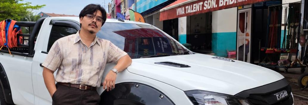 Muhammad Mustaqiim Roslan standing beside a white pickup